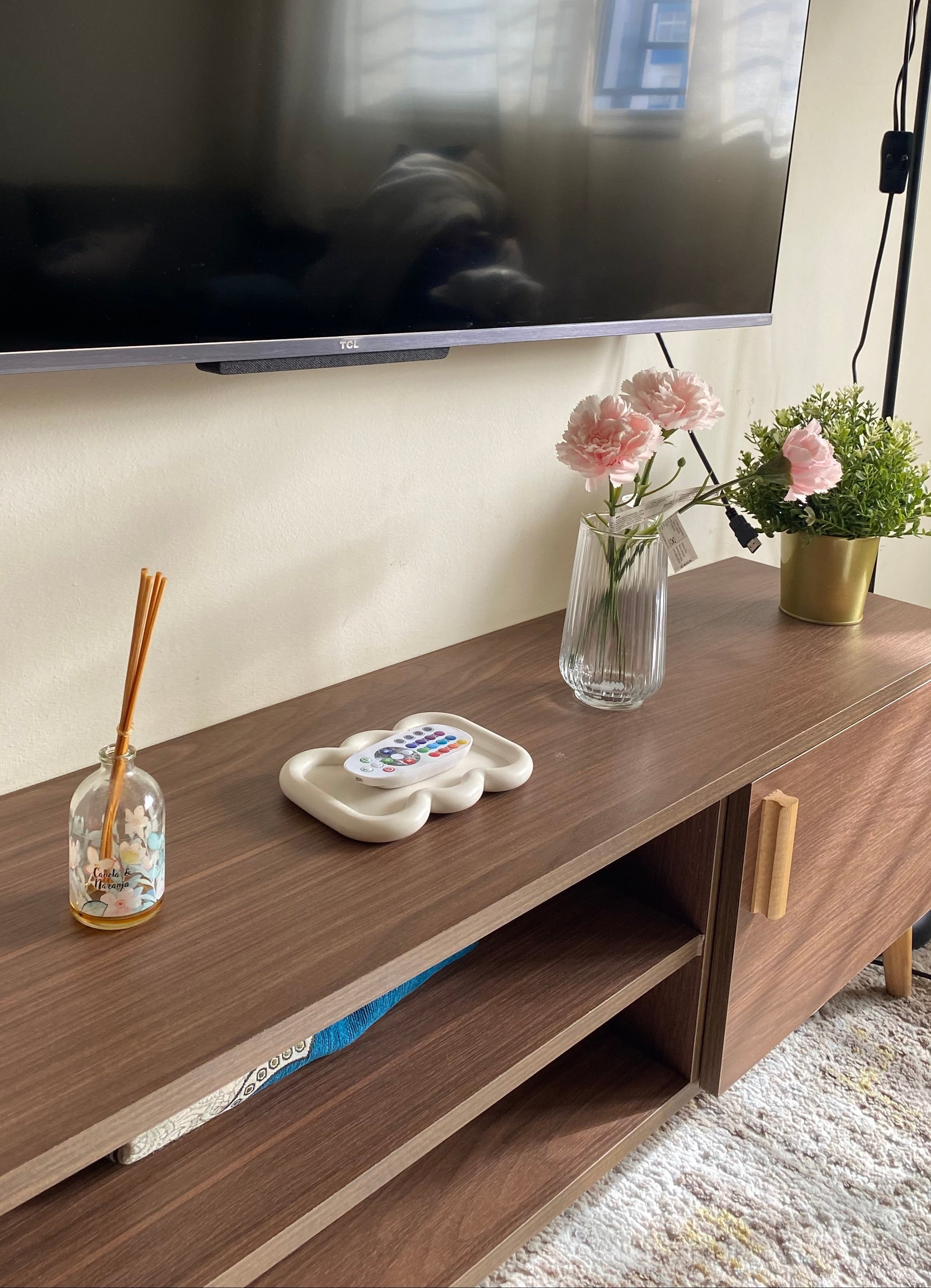 Plateau faro beige en jesmonite posé sur un meuble tv en bois.