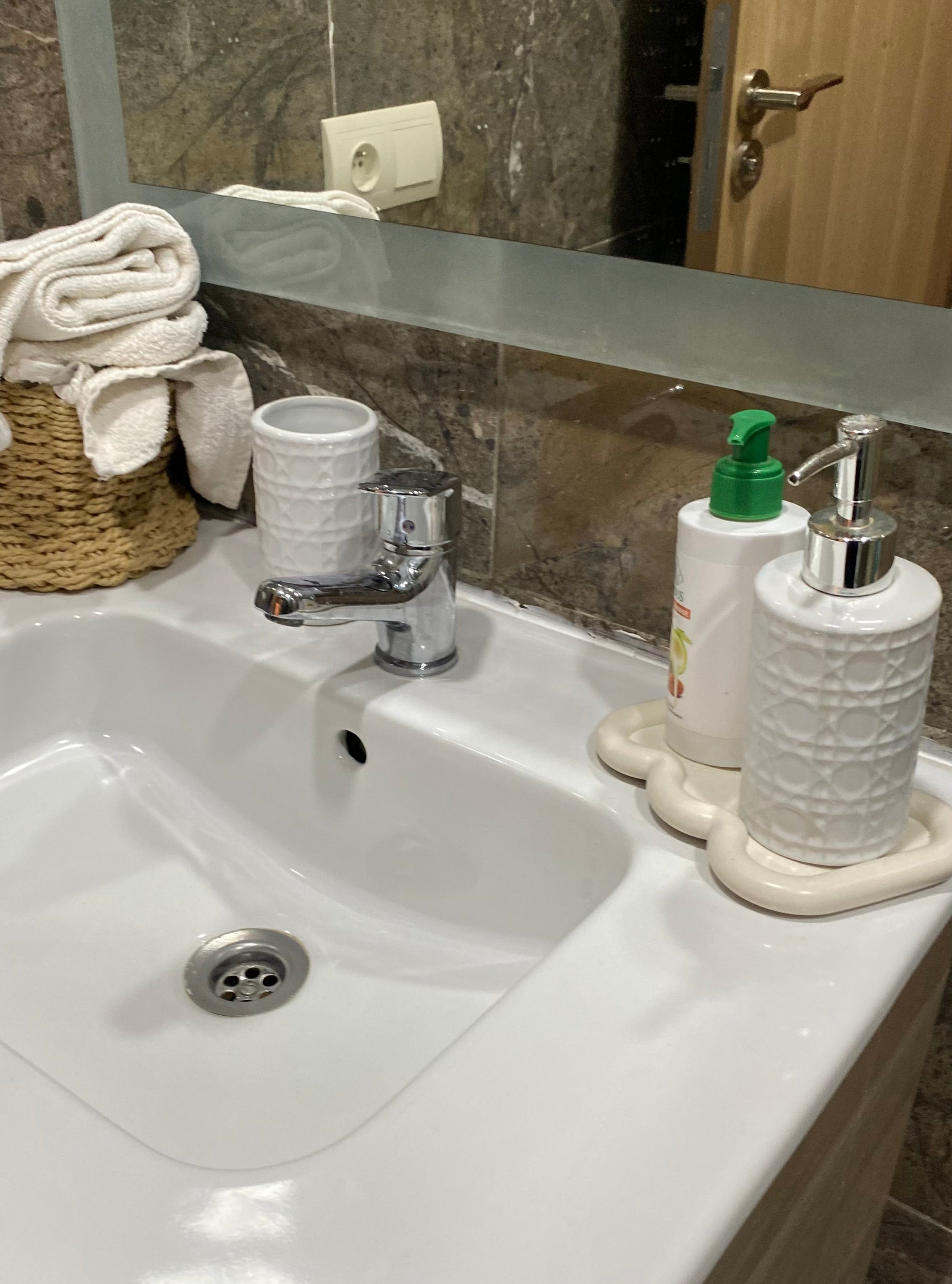 plateau beige en jesmonite ondulé beige posé sur l'évier dans une salle de bain.