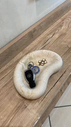 plateau jesmonite posé sur un support en bois à l'entré et ou il y a à l'intérieur des clés de voitures et un petit bracelet