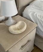 plateau jesmonite beige marbré posé sur une table de chevet