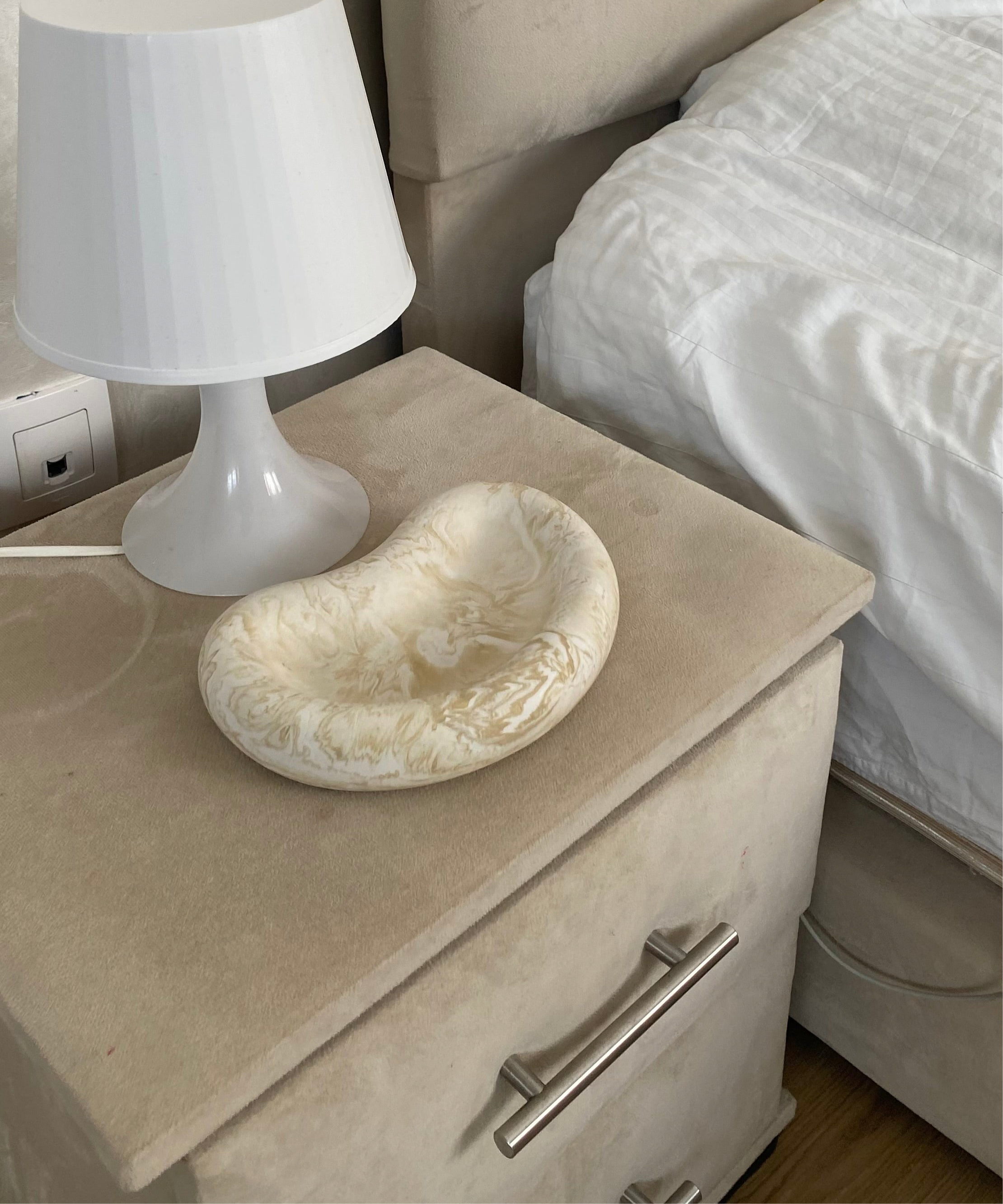 plateau jesmonite beige marbré posé sur une table de chevet