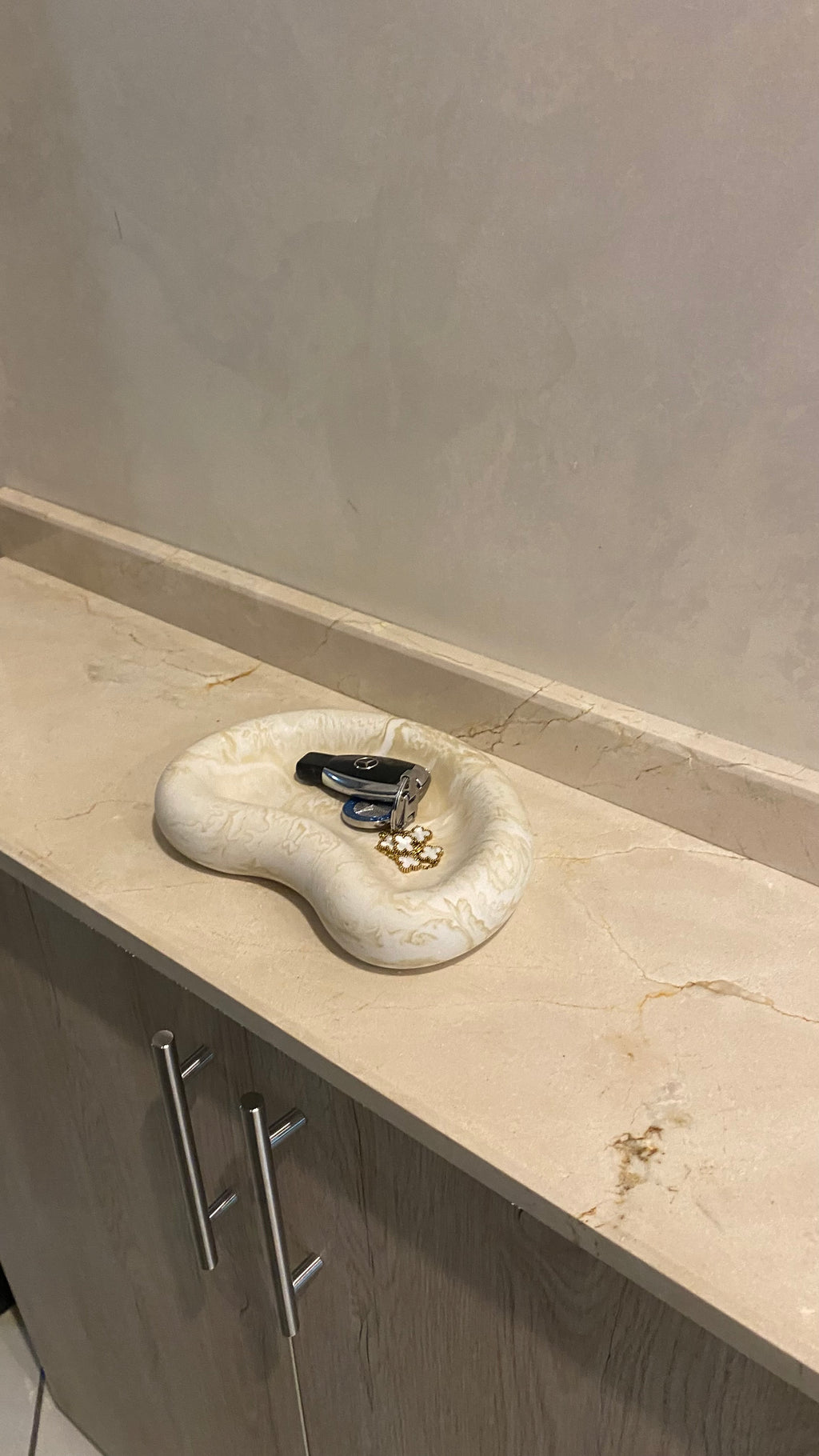 plateau jesmonite beige marbré posé dans une entrée avec des clés à l'intérieur