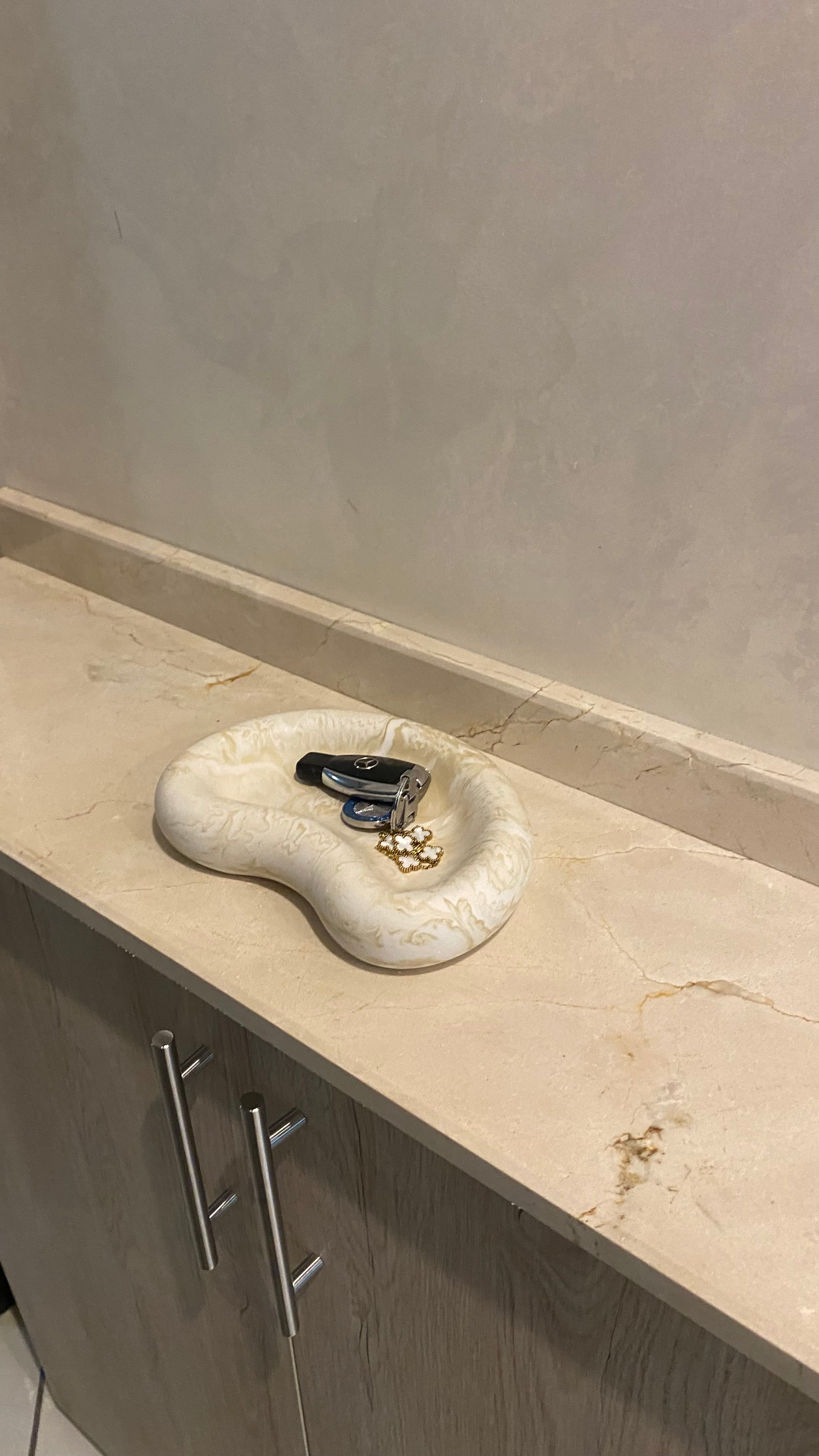 plateau jesmonite beige marbré posé dans une entrée avec des clés à l'intérieur