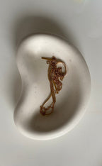 plateau blanc en jesmonite avec un collier dedans