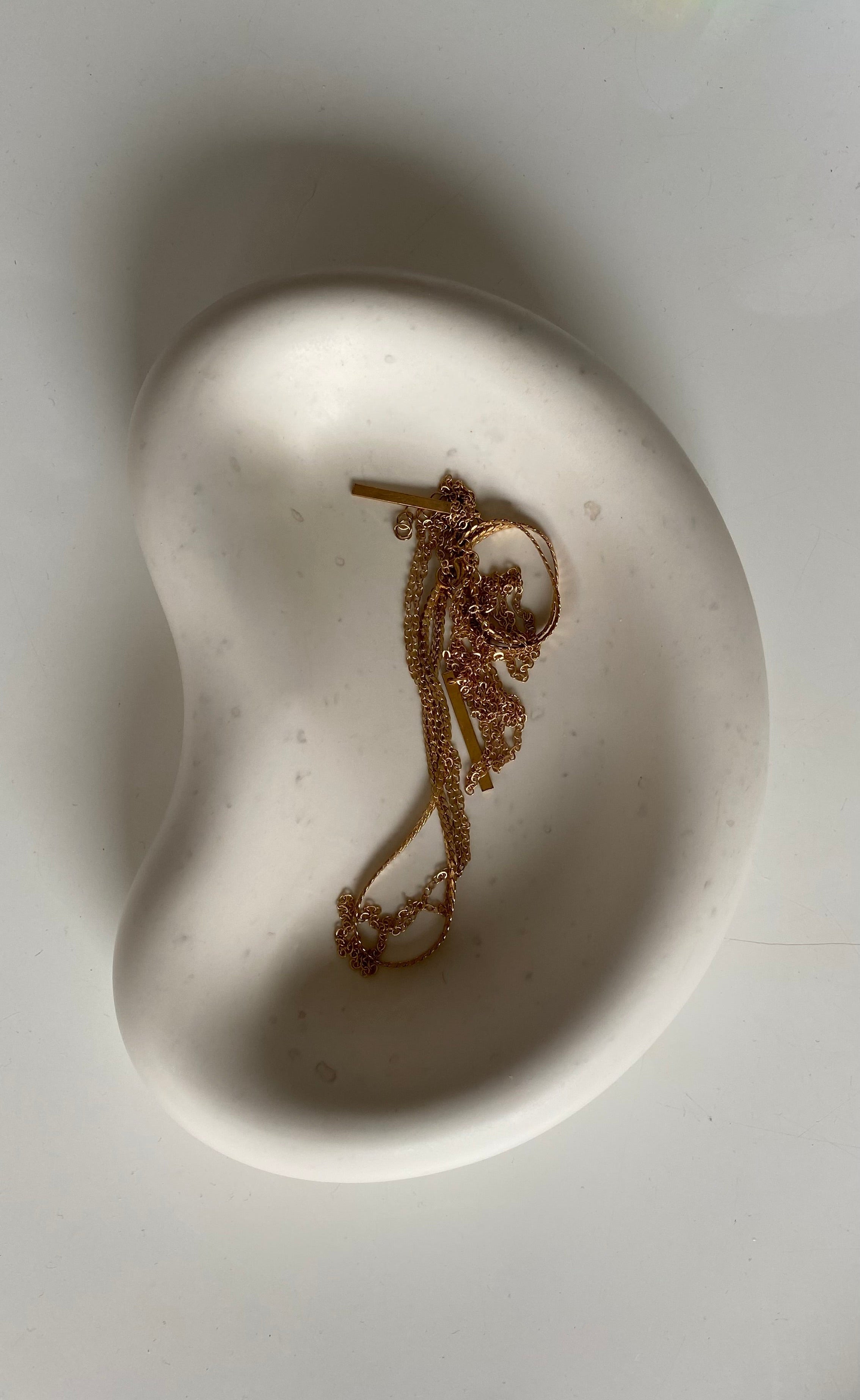 plateau blanc en jesmonite avec un collier dedans